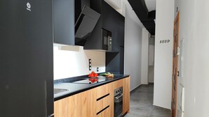 Een moderne keuken met zwarte kastjes, houten aanrecht en een ingebouwde oven.