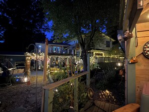 An outdoor area with a wooden deck, string lights, and a clock on the wall.