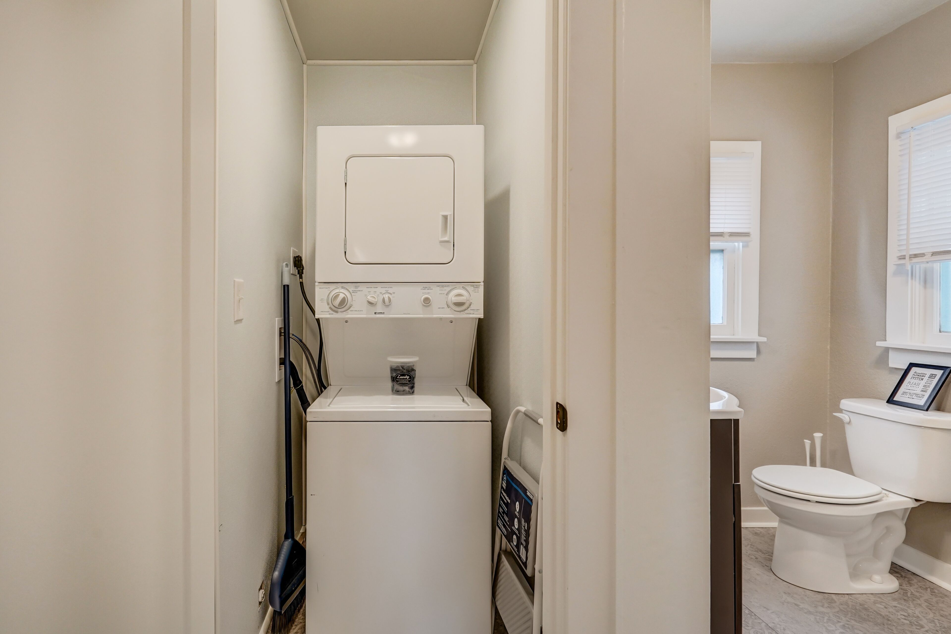 A compact laundry room with a washer and dryer, a toilet, and a small sink.