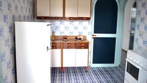 A kitchen with patterned tiles, wooden cabinets, a white refrigerator, and a stove. - Nami Holiday Home for six Guests With Outdoor Space (Melendugno)