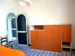 A room with a wardrobe, a chair, and a patterned floor.