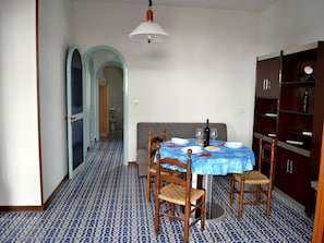 A dining area with a table set for four, a bookshelf, and a patterned floor.