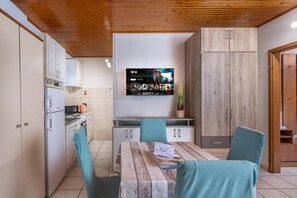 Une cuisine moderne avec des meubles blancs, un plafond en bois et un coin repas comprenant une table et des chaises en bois.
