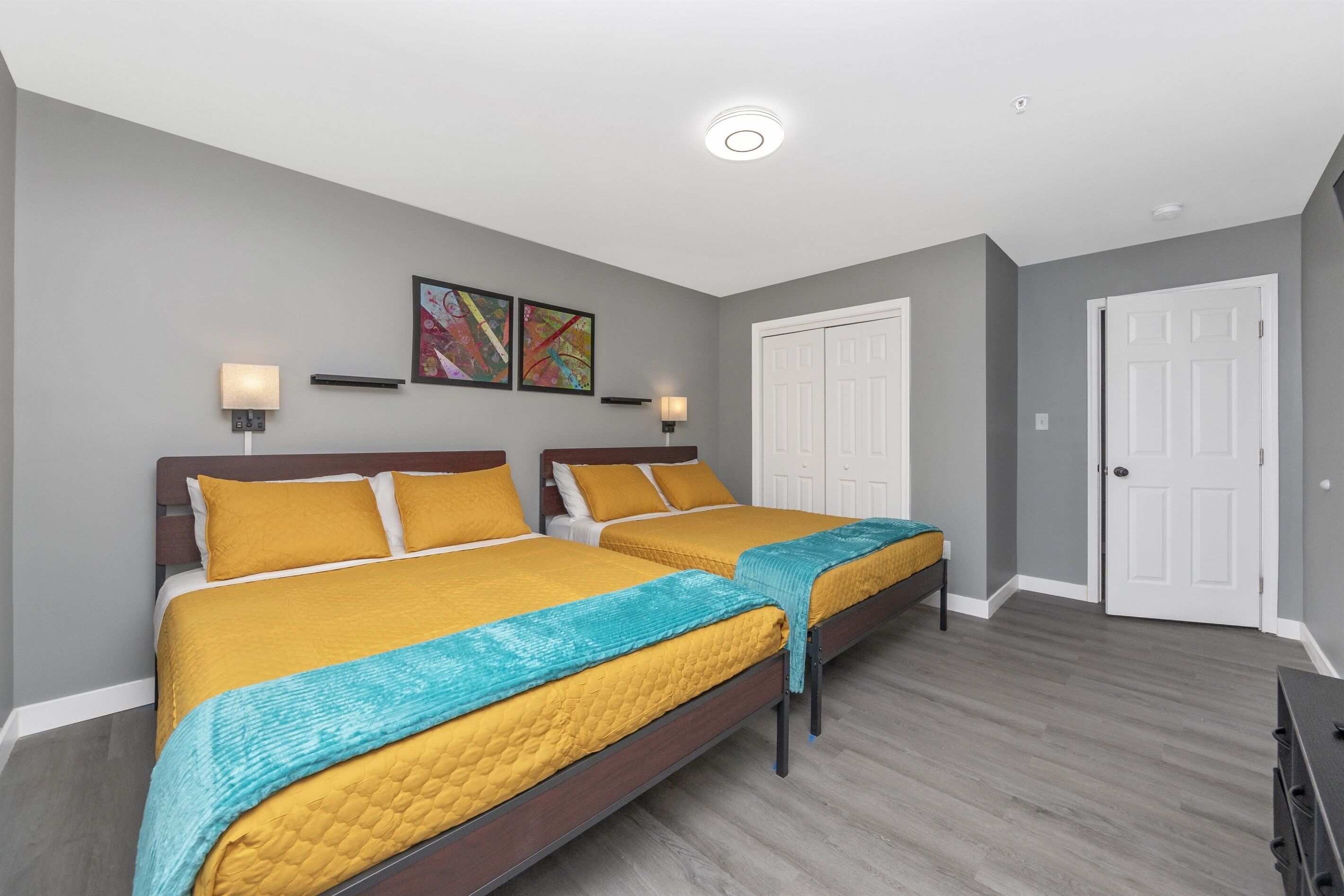 A bedroom with two beds, grey walls, and a white door.