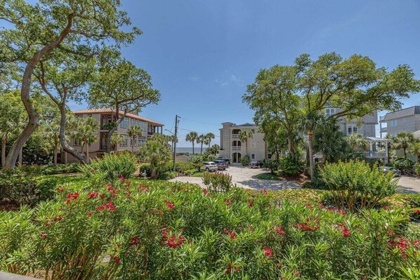 Uma área residencial com uma casa grande, um edifício menor e um jardim bem cuidado com flores vermelhas.