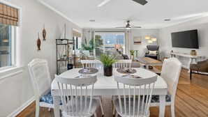 A dining area with a white table and chairs, a ceiling fan, and a view of the city.