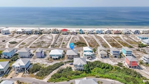 Un quartier résidentiel situé sur la côte, composé de plusieurs maisons, dont certaines donnent directement sur la plage, et offrant une vue dégagée sur l’océan.