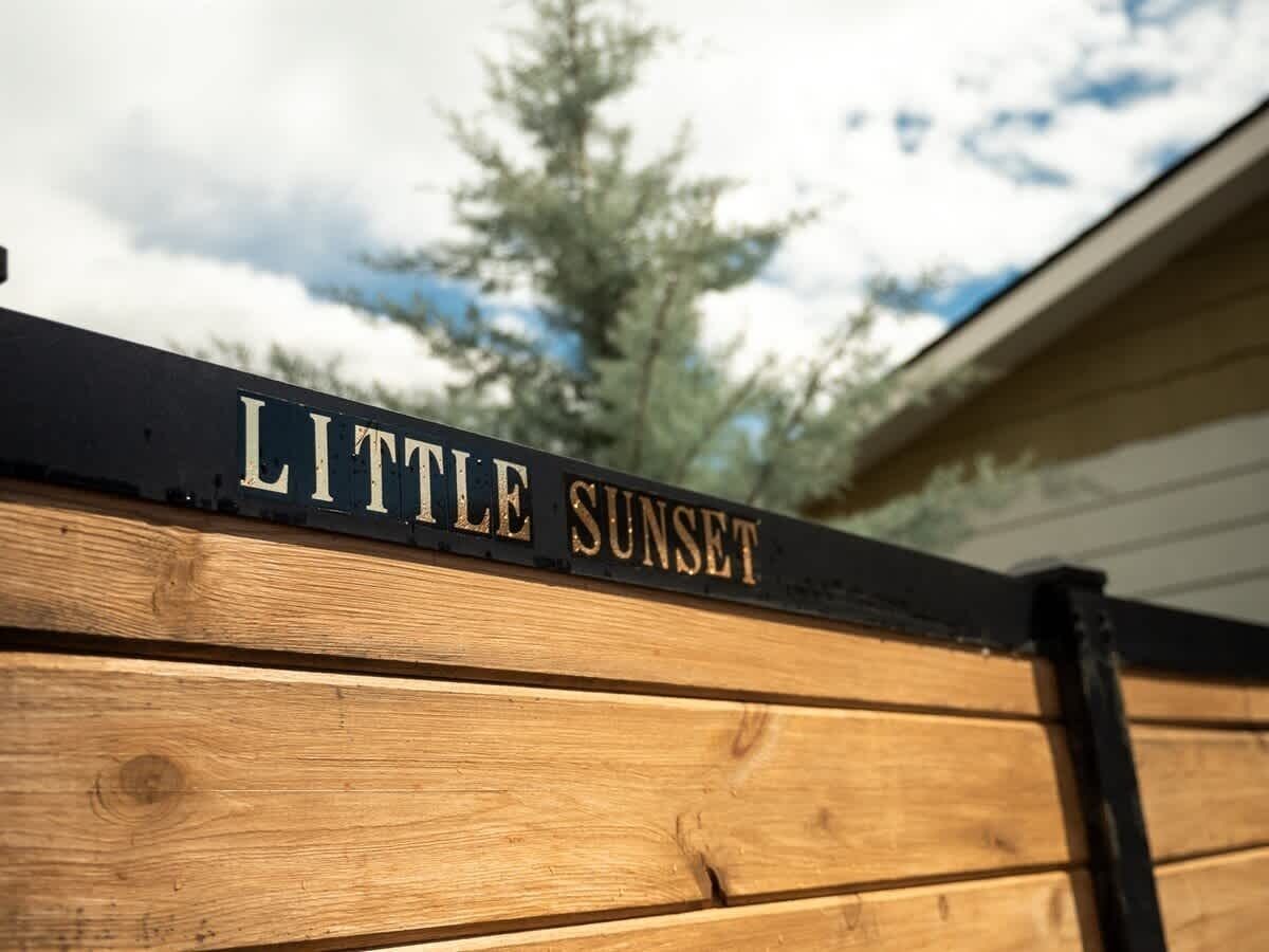 Ein Holzzaun mit einem Schild, auf dem 'LITTLE SUNSET' steht.