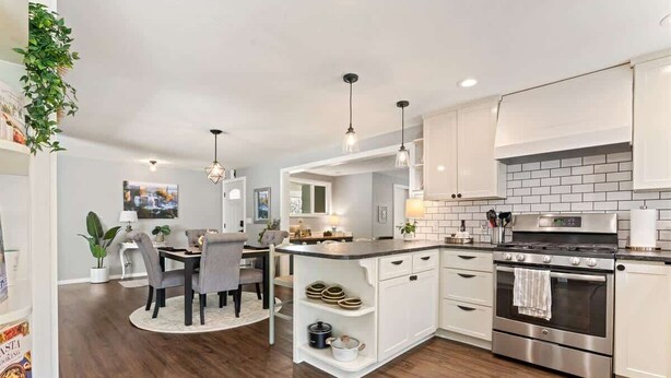 A modern kitchen with white cabinets, a central island, stainless steel appliances, and pendant lighting.