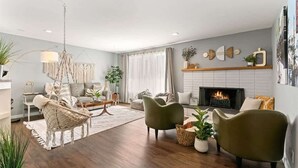 A modern living room with a fireplace, comfortable seating, and a hanging light fixture.