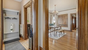 A spacious room with wooden flooring, a dining area with a chandelier, and a view of the outdoors.