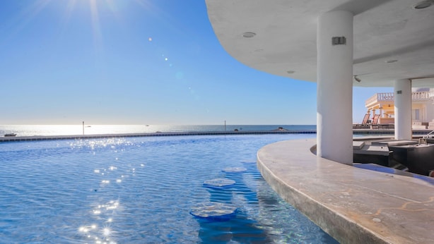 Una piscina con vista despejada al océano y un edificio de techo curvo.
