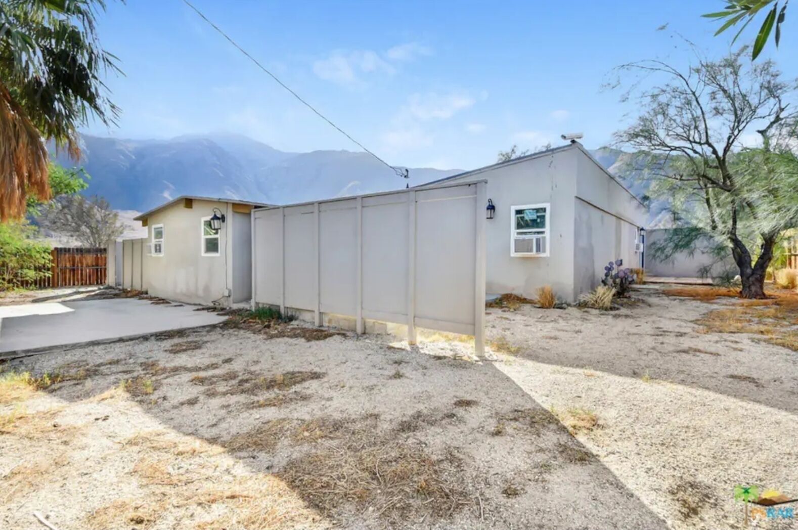 A single-story house with a garage, a fenced backyard, and a mountain backdrop.