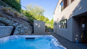 A modern house with a swimming pool, a stone retaining wall, and a large tree. - NEW! Beautiful large home with lake & mountain views and a hot tub. (Queenstown)
