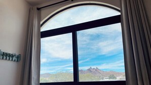 Una habitación con un amplio ventanal de arco, una cortina y una lámpara fijada a la pared.