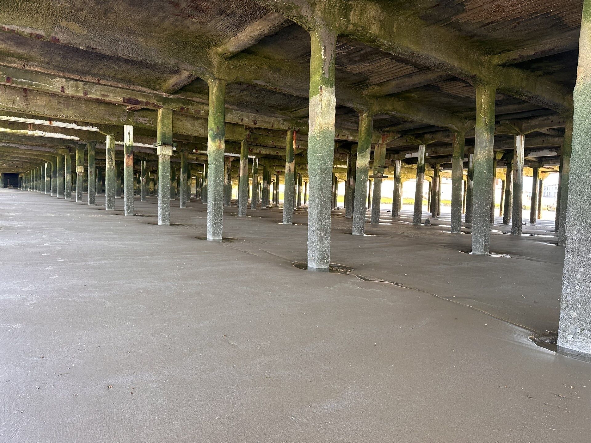An abandoned building with a long corridor and numerous columns.