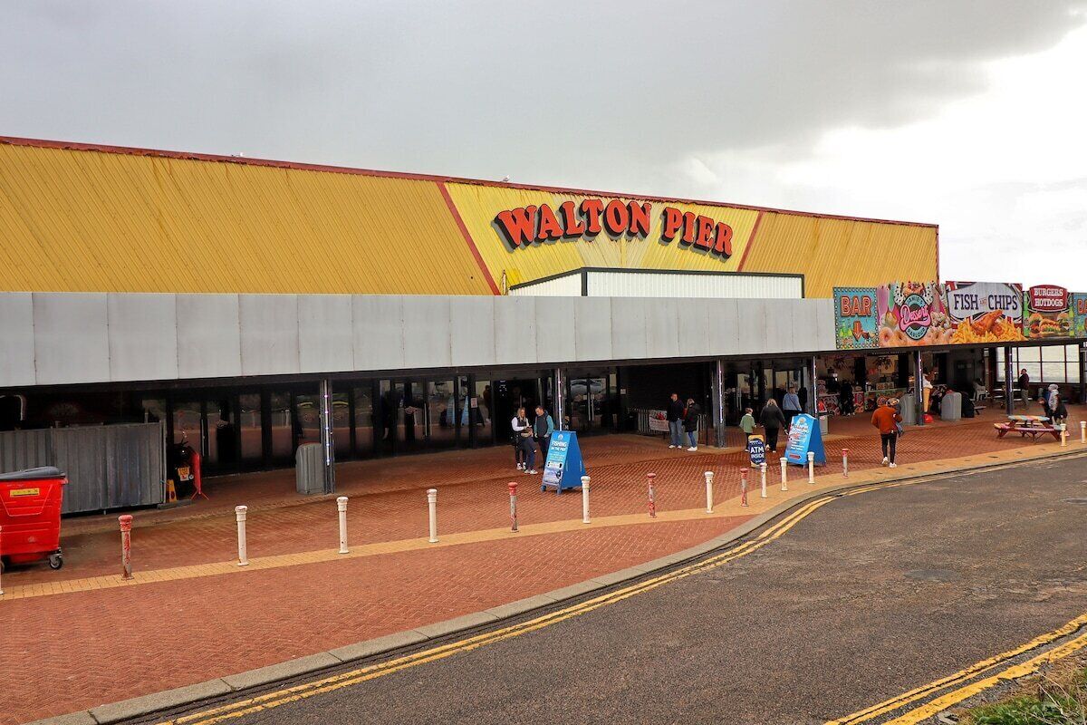 The exterior of a Walton Pier building with a yellow facade, a signboard, and a pedestrian entrance.