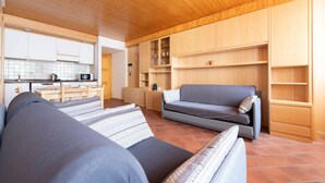 A modern, compact living space with a kitchenette, a sofa, and built-in wooden shelving. - Bruni 2 in Bormio With 1 Bedrooms and 1 Bathrooms (Bormio)
