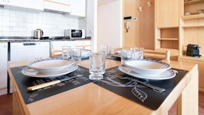 A dining table set with plates, glasses, and cutlery, with a microwave and kettle in the background. - Bruni 2 in Bormio With 1 Bedrooms and 1 Bathrooms (Bormio)