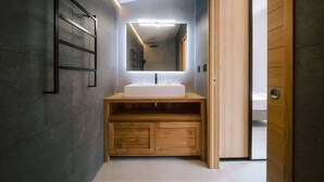 Ein modernes Badezimmer mit großem Spiegel, Holzwaschtisch und einer deckenebnen Leuchte.