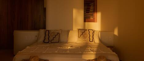 A bedroom with a bed, two nightstands, a ceiling fan, an air conditioning unit, and a window with blinds.
