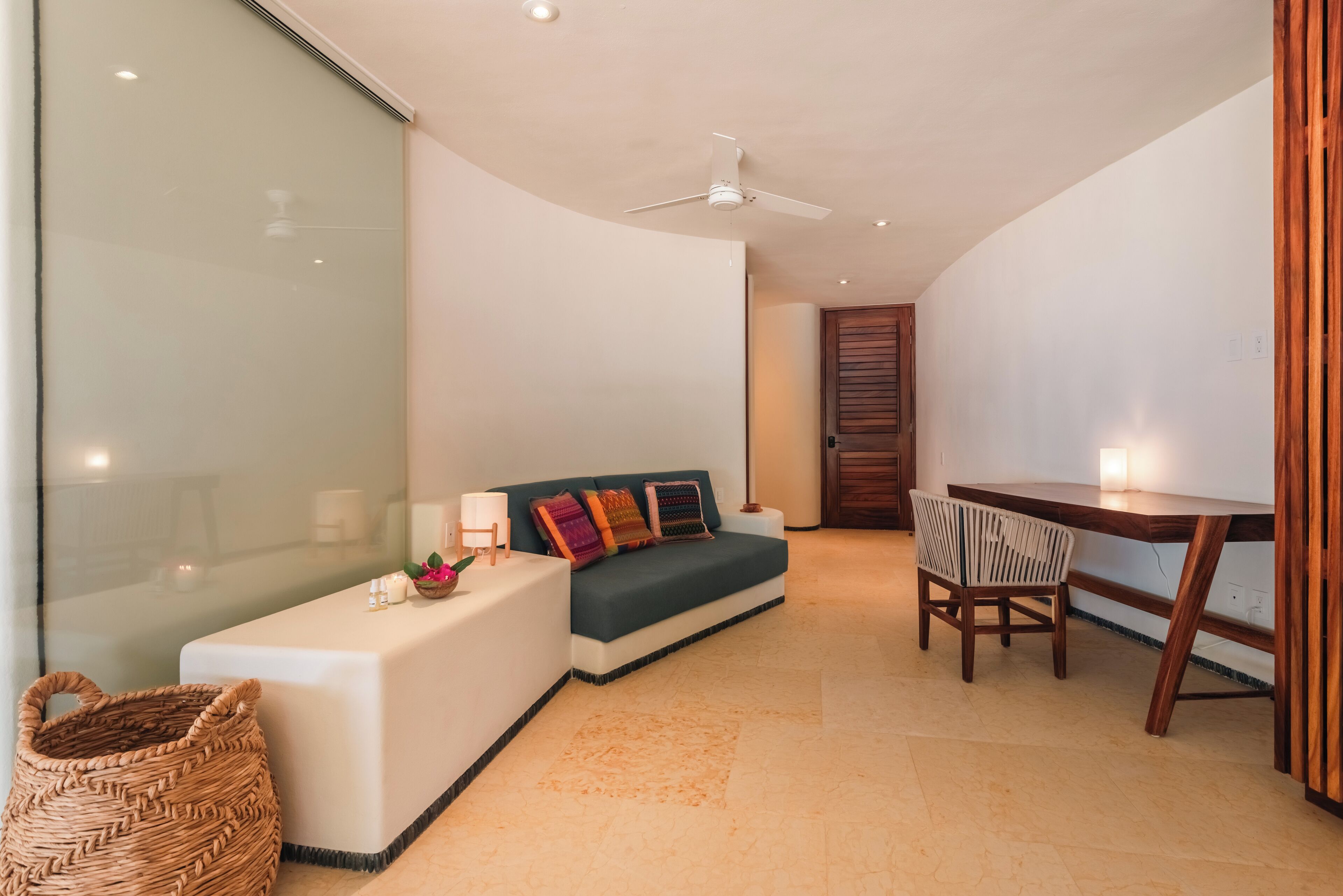 A modern living room with a sofa, a dining table, and a ceiling fan.