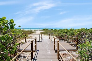 A wooden boardwalk leading to a beach with clear skies.