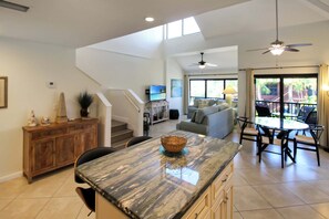 A spacious living area with a kitchen, dining area, and a staircase leading to an upper level.