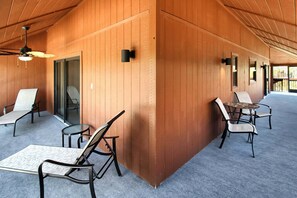 Ein überdachter Außenbereich mit Stühlen und Tischen, Holzwänden und einem Deckenventilator.