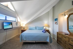 A bedroom with a bed, nightstands, a TV, a mirror, and a wooden dresser.