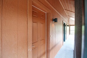 A corridor with wooden walls and doors, a light fixture, and a visible door handle.
