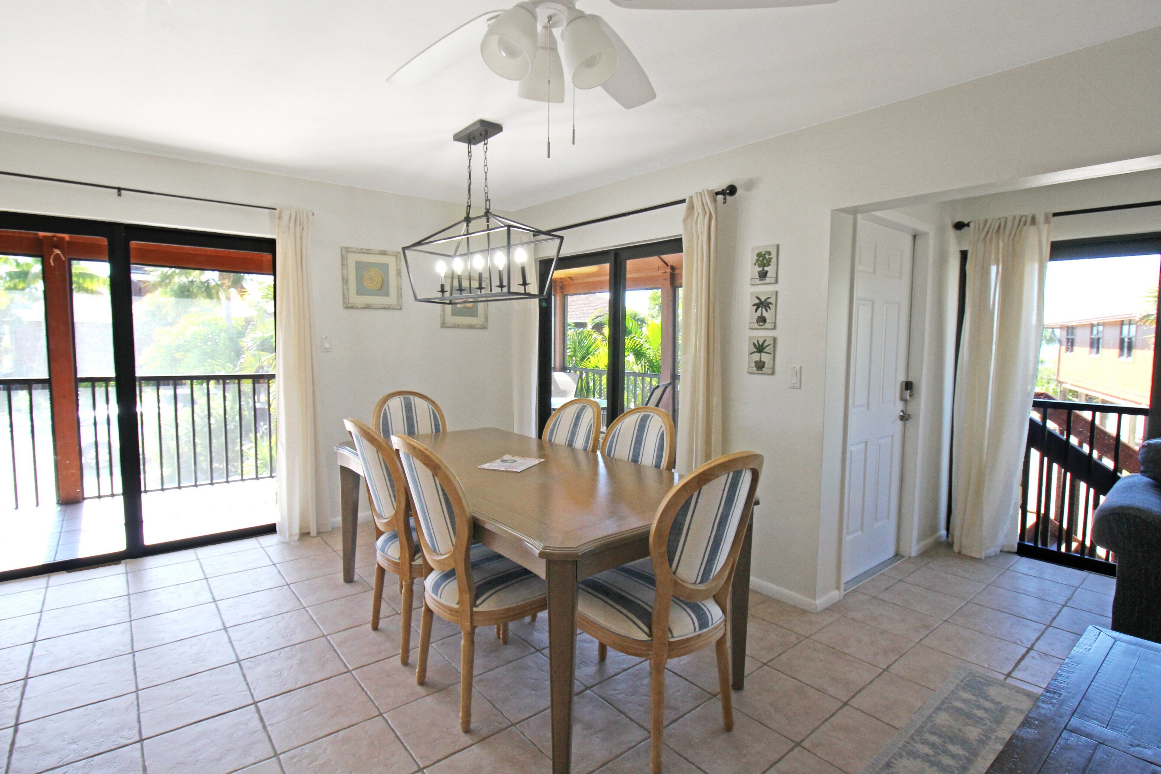 A dining area with a table and chairs, a ceiling fan, and a view through a sliding door to an outdoor balcony.