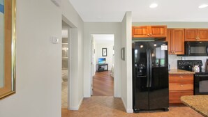 A modern kitchen with a refrigerator, microwave, and stove. There is a wooden cabinet and a countertop. - Pet friendly 3BR Villa with Gulf Views & Rooftop Sundeck - Private Beach - Signal Inn 17 (Sanibel)