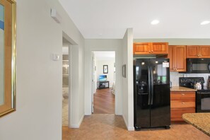 A modern kitchen with a refrigerator, microwave, and stove. There is a wooden cabinet and a countertop. - Pet friendly 3BR Villa with Gulf Views & Rooftop Sundeck - Private Beach - Signal Inn 17 (Sanibel)