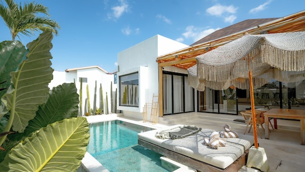 A modern pool area with a clear pool, a lounge with a canopy, and a large plant. - Villa Rosado Canggu (Canggu)