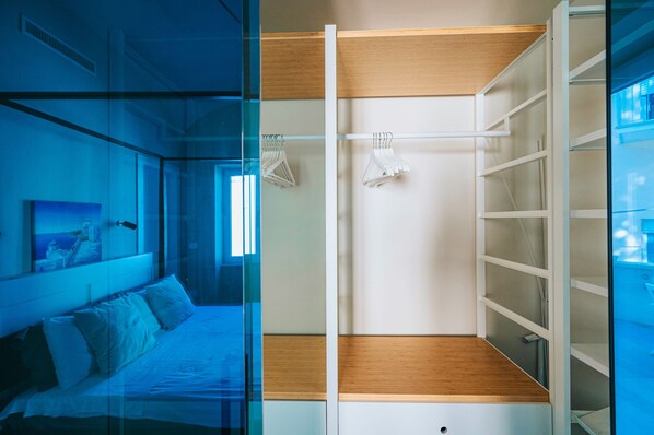 A bedroom with a bed, a glass partition, and a wardrobe with shelves.