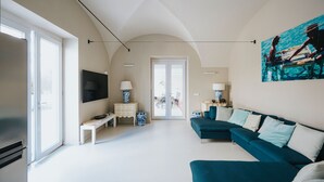 A modern living room with a large TV, a sofa, and a painting of a couple on a boat. - Villa Matilde by Elite Villas (Capri)