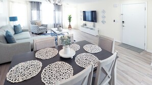 Un salon moderne avec une table à manger, un canapé et un téléviseur.