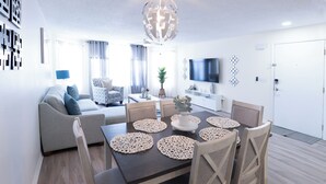 Un salon moderne avec une table à manger, un canapé et un téléviseur.