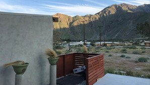 Un patio con vistas a montañas, cerca de una valla de madera y un muro de concreto.