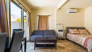 Una habitación de hotel moderna con sofá, cama, una mesita y una ventana con cortinas.