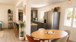 Une cuisine moderne avec un coin repas, un plancher en bois et une grande fenêtre.