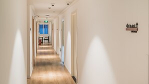 A hotel corridor with a wooden floor, white walls, and a sign indicating the direction to the laundry.