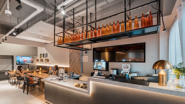 A modern restaurant with a bar area, seating, and a counter with a computer and a TV.