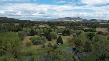 A rural landscape with multiple houses surrounded by dense vegetation and hills in the background.