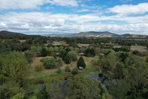 A rural landscape with multiple houses surrounded by dense vegetation and hills in the background. - StayAU 3BR Quaint Countryside Cottage (Badger Creek)