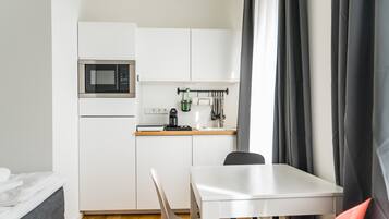 Eine kompakte Küche mit Mikrowelle, Kaffeemaschine und Küchenutensilien, die an der Wand hängen.