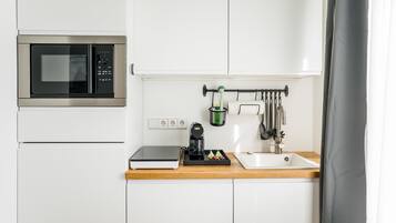 Eine kompakte Küche mit Mikrowelle, Kaffeemaschine und Spüle.