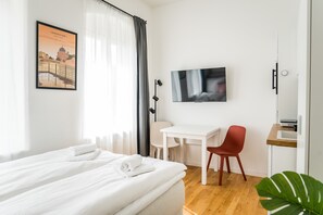 Ein Hotelzimmer mit Bett, Schreibtisch, Fernseher und einem Fenster mit Vorhängen.