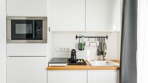 Cocina pequeña equipada con microondas, cafetera y lavamanos.